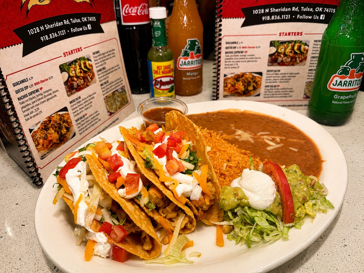 Crispy hard-shell taco combo with sour cream, tomato, rice, beans, and guacamole at Los Primos