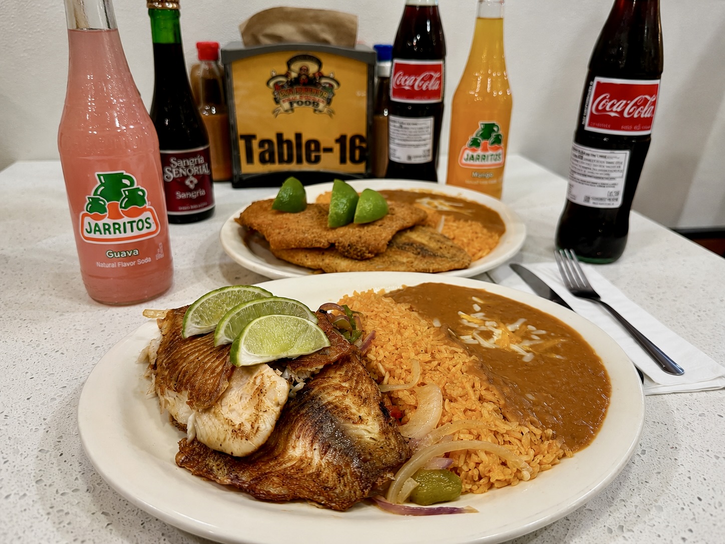 Grilled and fried tilapia plates with rice and beans at Los Primos