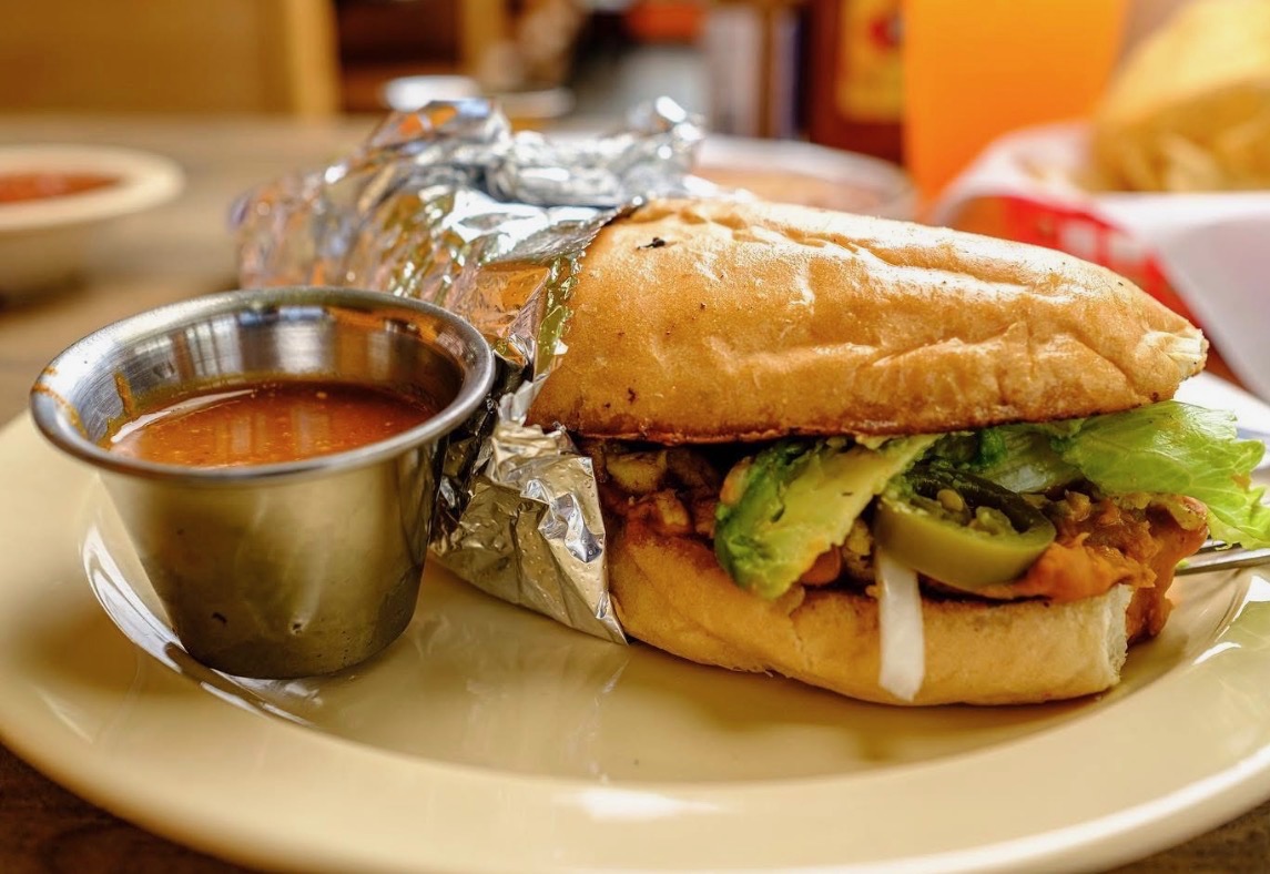 Torta sandwich wrapped in foil, served with a cup of salsa at Los Primos