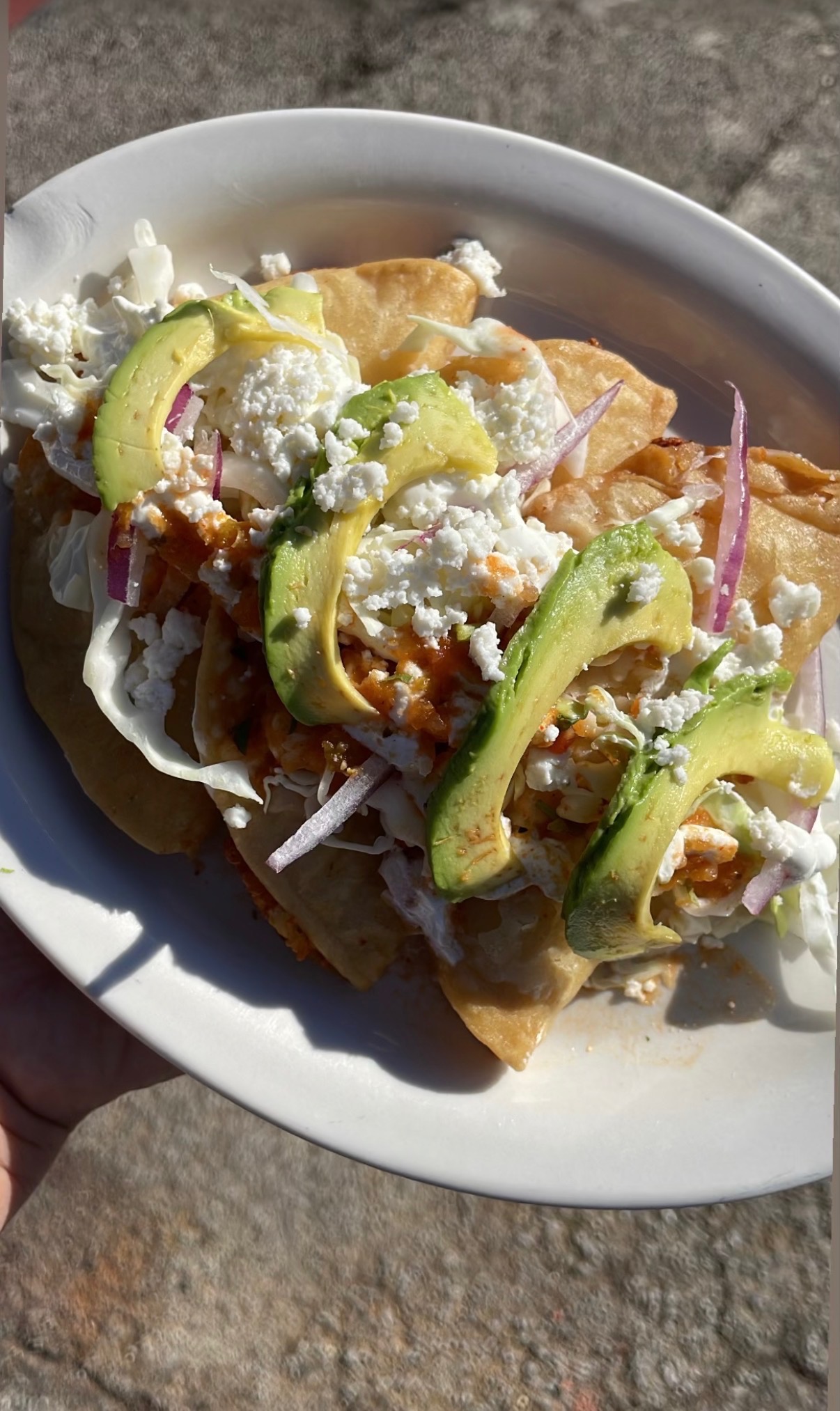 Crispy potato tacos dorados topped with cabbage, tomato, red onion, and queso fresco at Los Primos